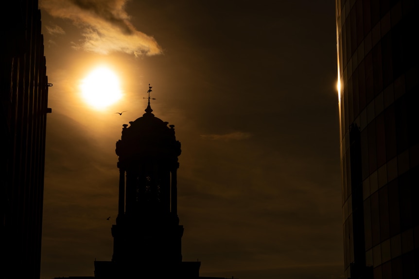 The sun sets in Glasgow, silhouetting a building.
