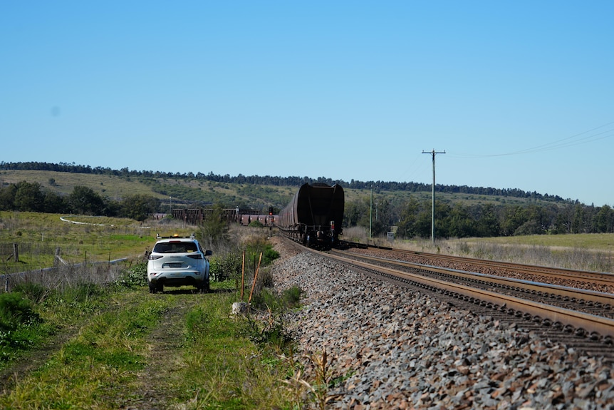 A long coal train on tracks in the countryside