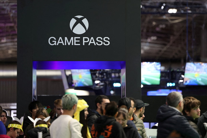 Xbox game pass logo on signage, with crowd below