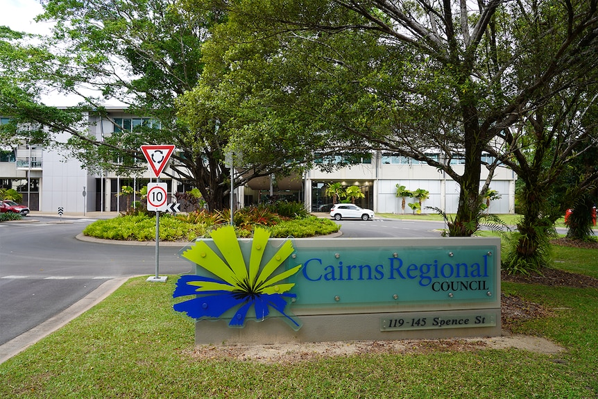 A sign that says "Cairns Regional Council" stands in front of a light-coloured building.