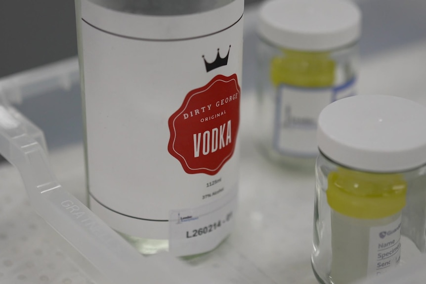 A large bottle of vodka sitting in a tray for lab testing.