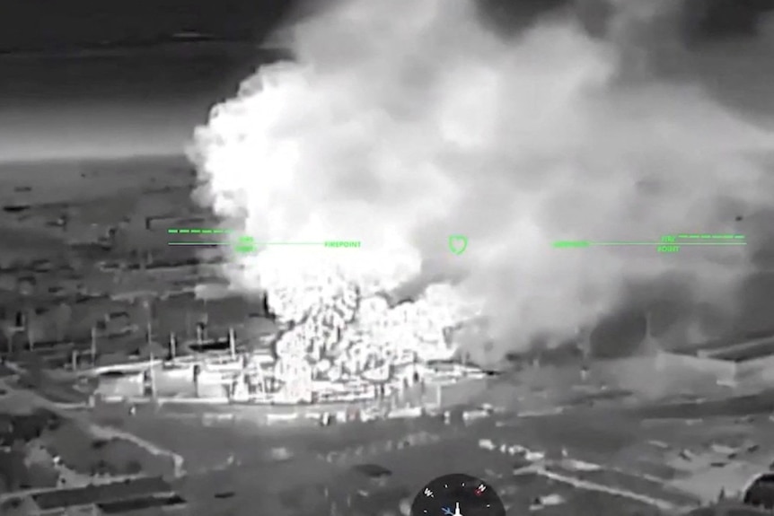 A large amount of smoke rises from a building, seen from the perspective of a drone in the sky.