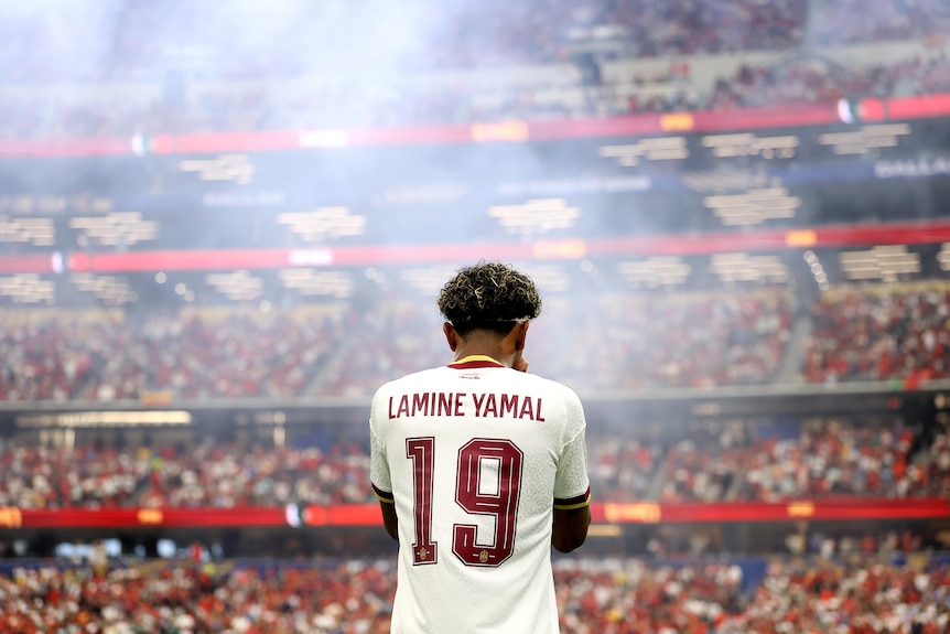 Shot from behind of Lamine Yamal with the stadium and crowd in the background