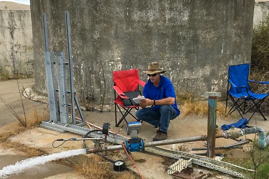 a man squats near a water pipe
