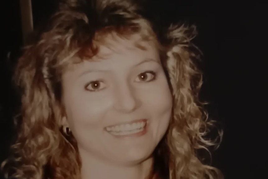 A woman with curly blonde hair smiles for the camera.