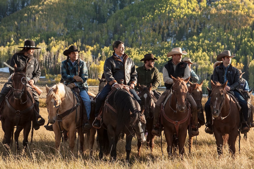 A group of men ride horses in a ranch.