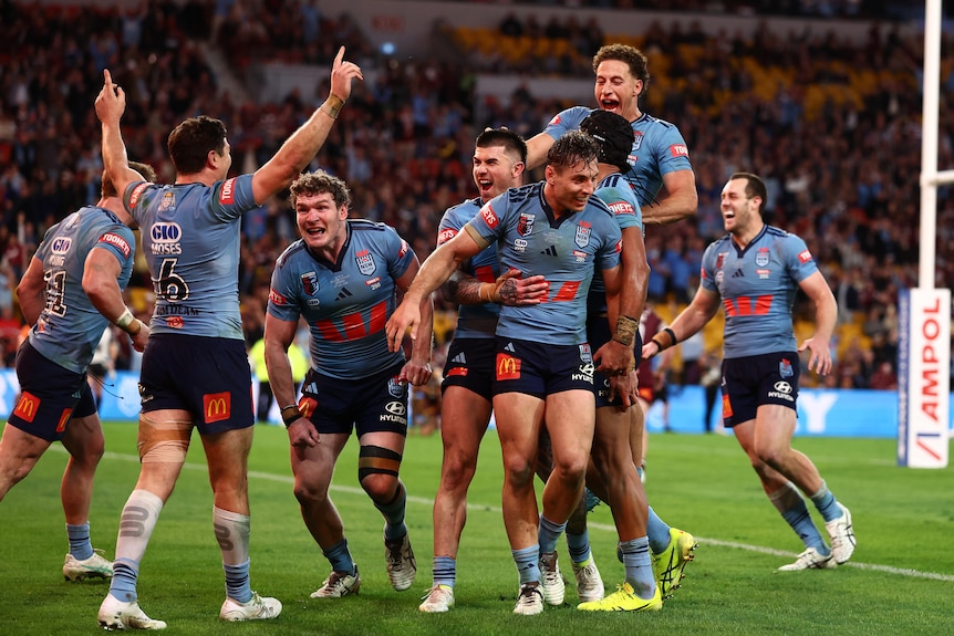 A group of rugby league players in blue celebrate a victory