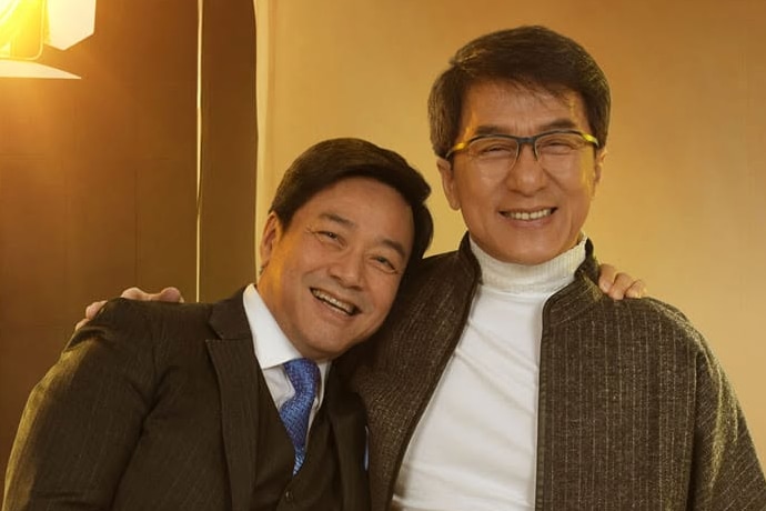 Two men in suits stand side by side and smile.
