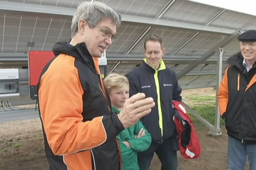 A close of a man in front a solar panel
