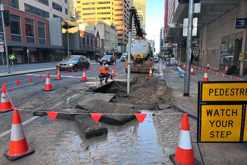 SA Water crew in high vis work on a city street with trucks and buildings in the background