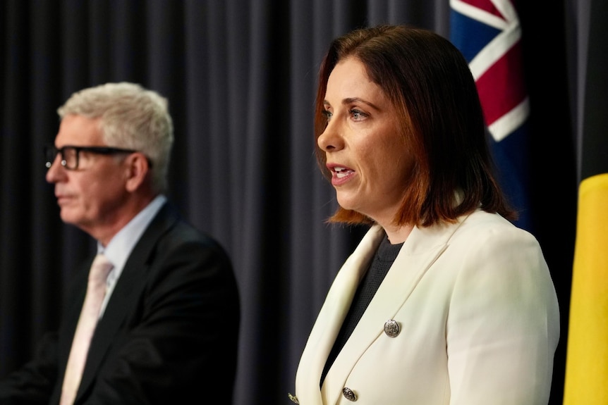 Adam Suckling on left and Anika Wells on right in front of Australian flag.
