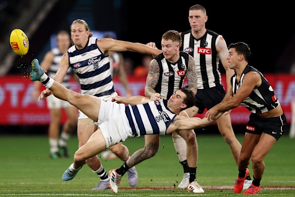 Mullin kicks the ball out of mid-air while being tackled by Nick Daicos (right).