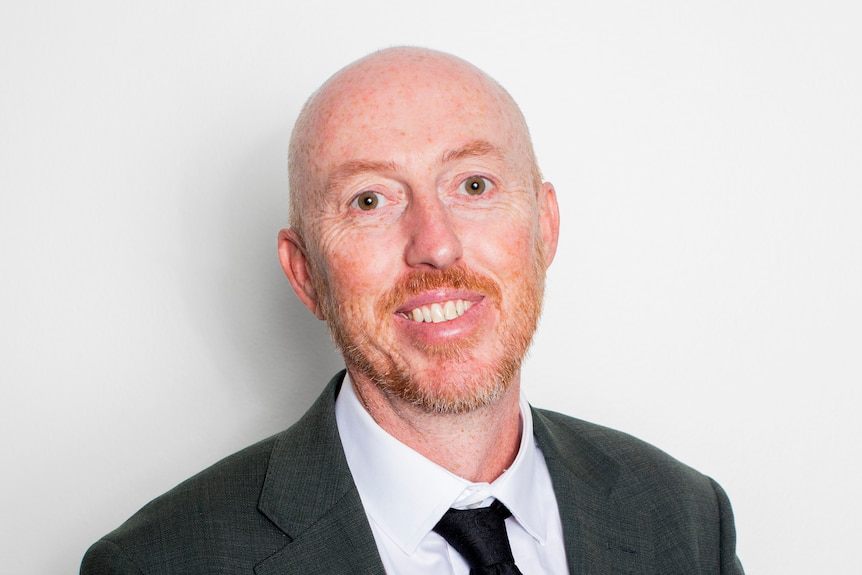 a man in a suit smiles at the camera