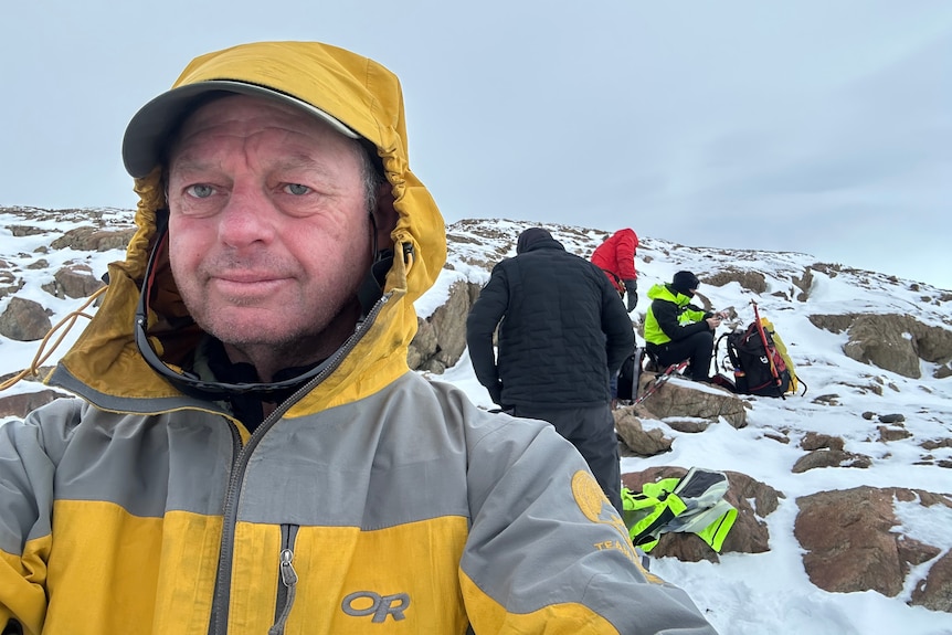 Man standing in front of others on a hill with snow