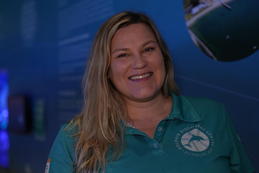 A blonde woman in a light blue polo shirt smiling at the camera.