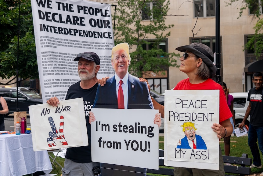 Protesters stand next to a cardboard cut-out of Trump.
