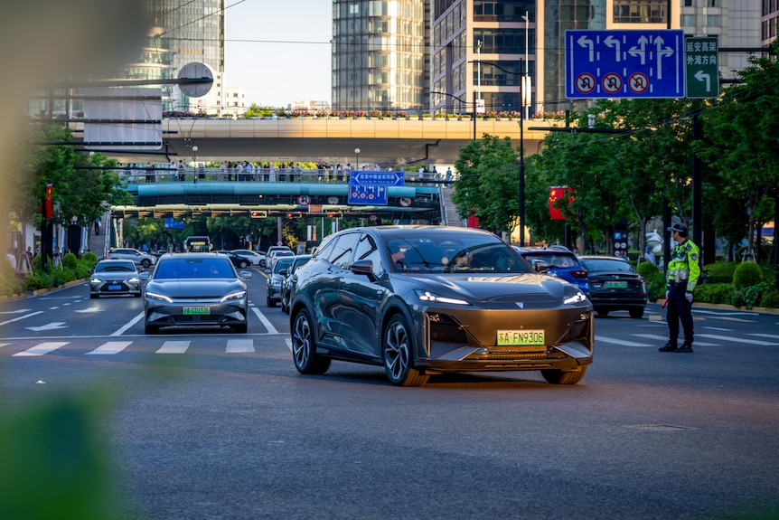 A car driving on a road with a green number plate, surrounded by other cars.