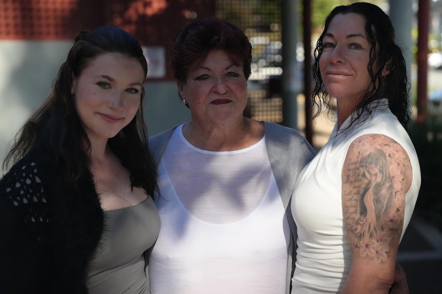 Three women look at the camera outside court.