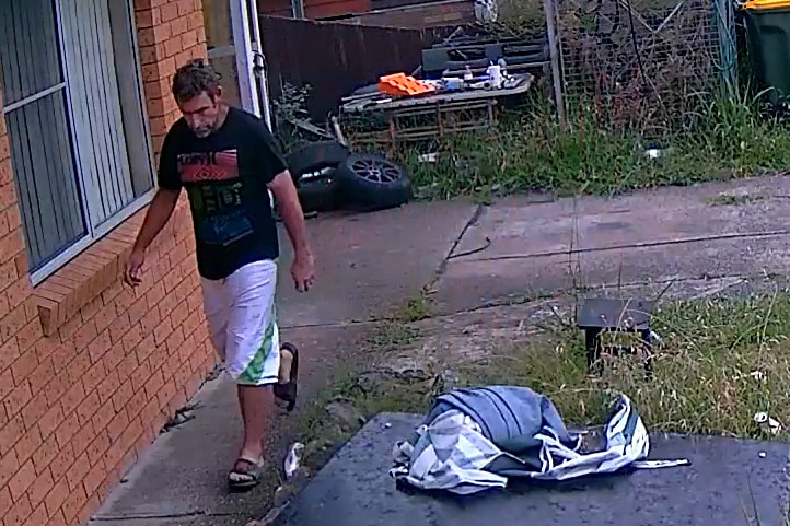 A CCTV still shows a man approaching a house.