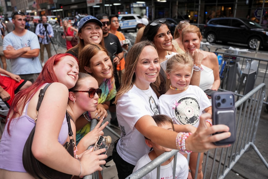 A mum takes a selfie with her young daughter and other Swifties on the street outside Madison Square Garden.