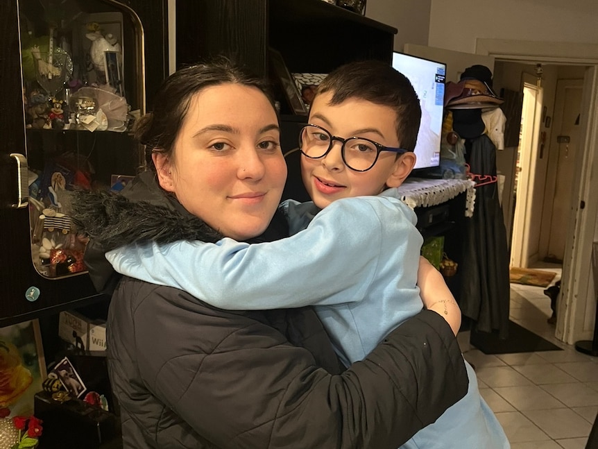 A young woman holder a younger brother in her arms in a hug