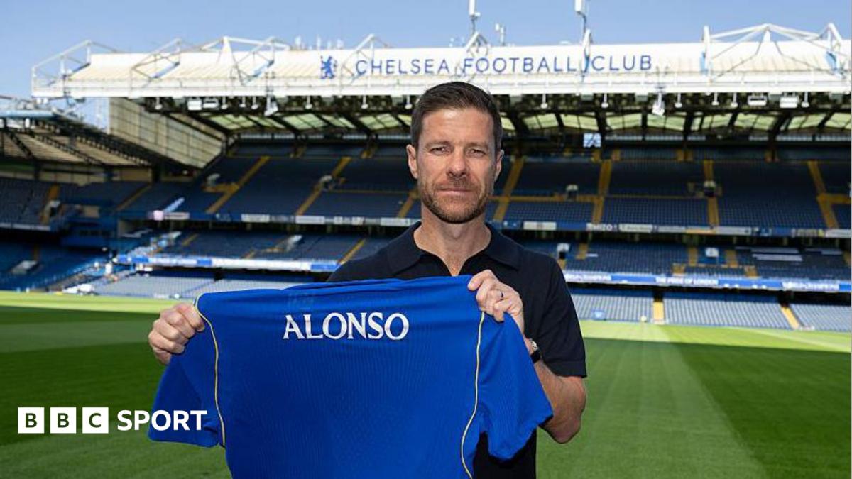 Xabi Alonso holding a Chelsea shirt while posing for a photo at Stamford Bridge