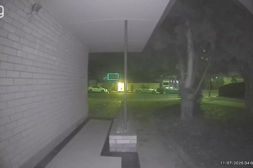 CCTV vision from across the st where you can see two white cars and a dark car, with a figure walking towards the house