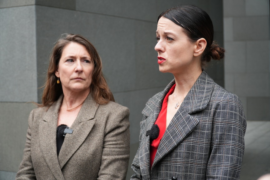 Joana and Kristen stand outside court wearing winter coats.