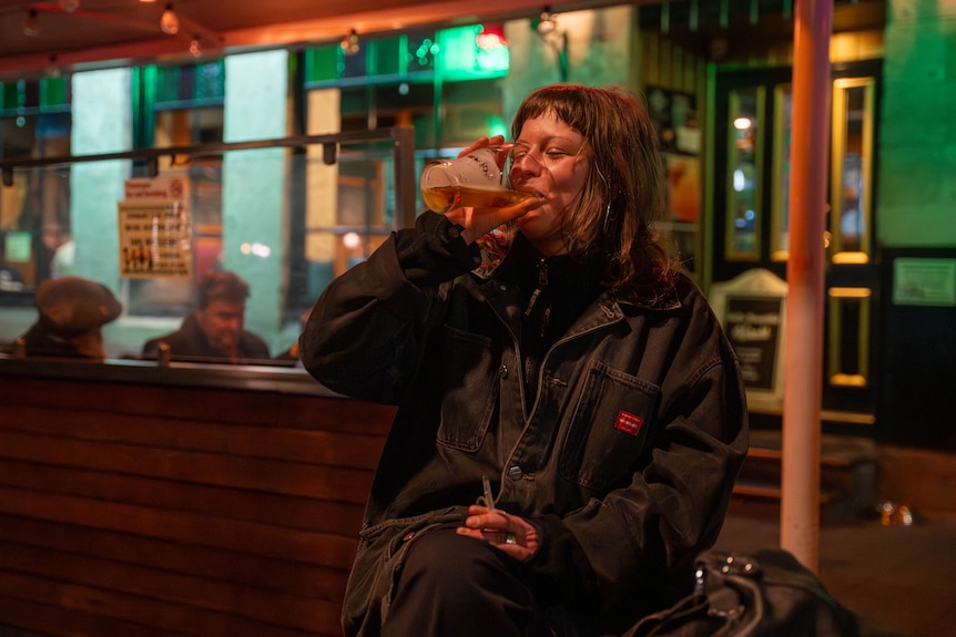 Woman drinking a beer whilst sitting and holding a cigarette