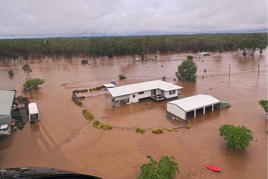 A home seen from a helicopter, surrounded by dirty floodwater