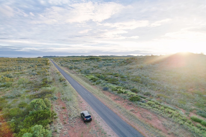 An aerial shot of a road stretching through the outback.