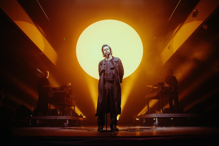 A man sings on a stage.