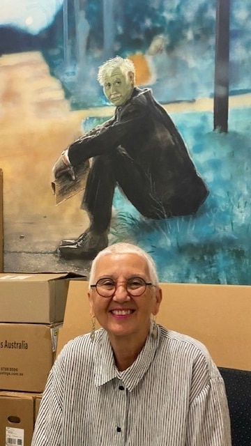Woman smiling in front of portrait of man sitting on curb