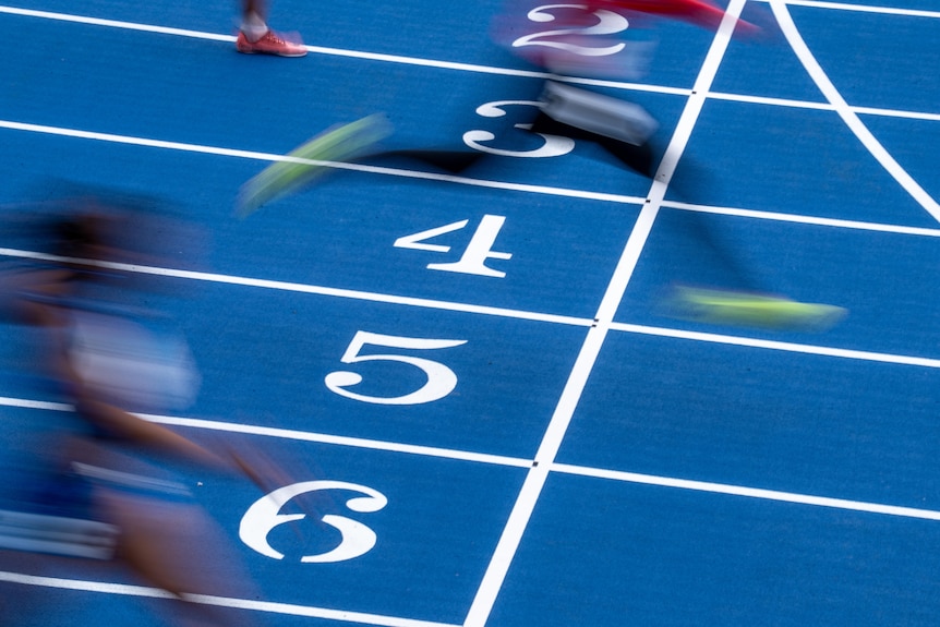 Runners cross the line in an athletics race.