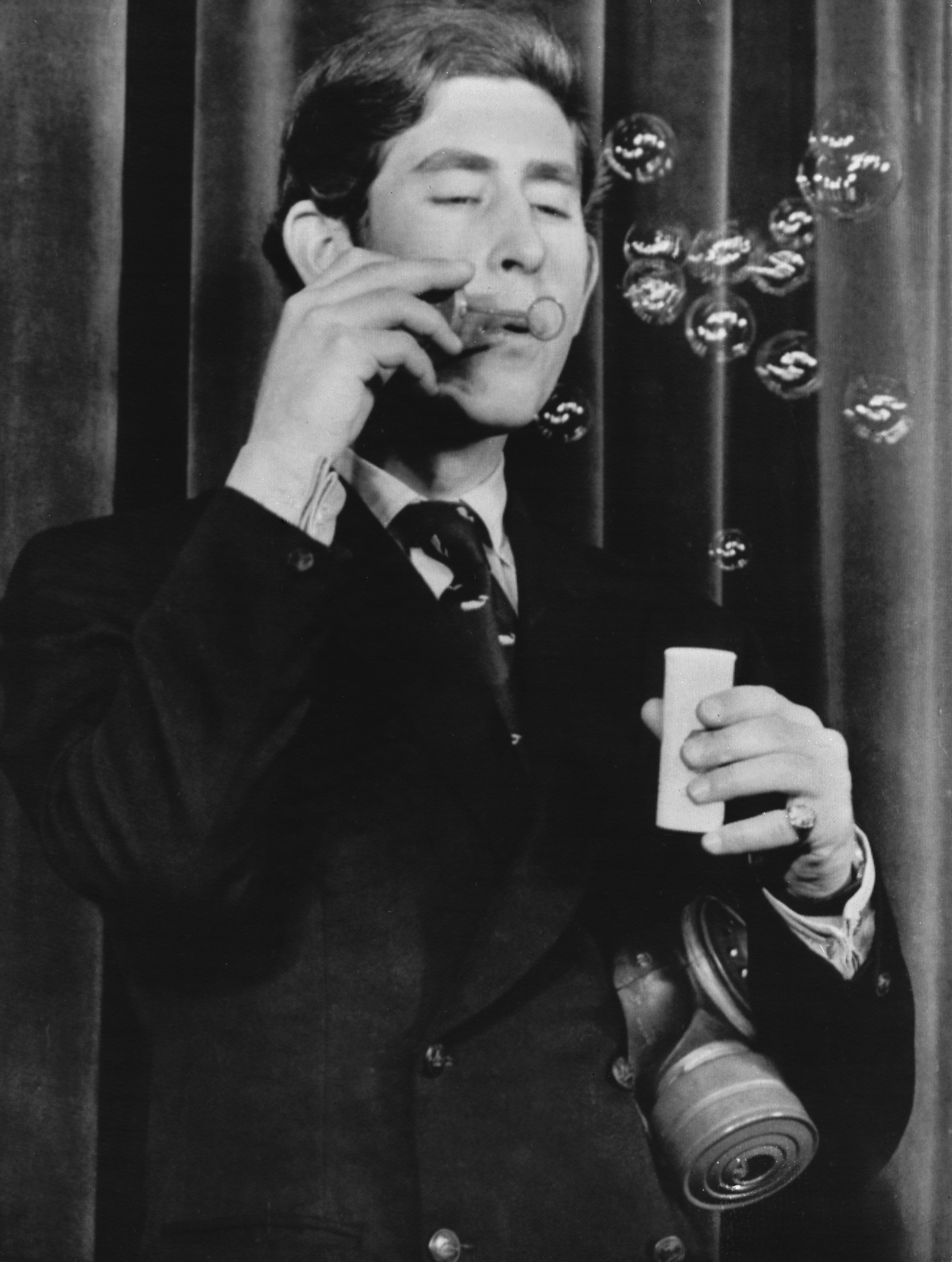 black and white photograph of Prince Charles in 1970 blowing bubbles on stage at Cambridge University