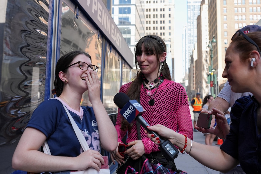 A girl smiles and puts her hand over her mouth.