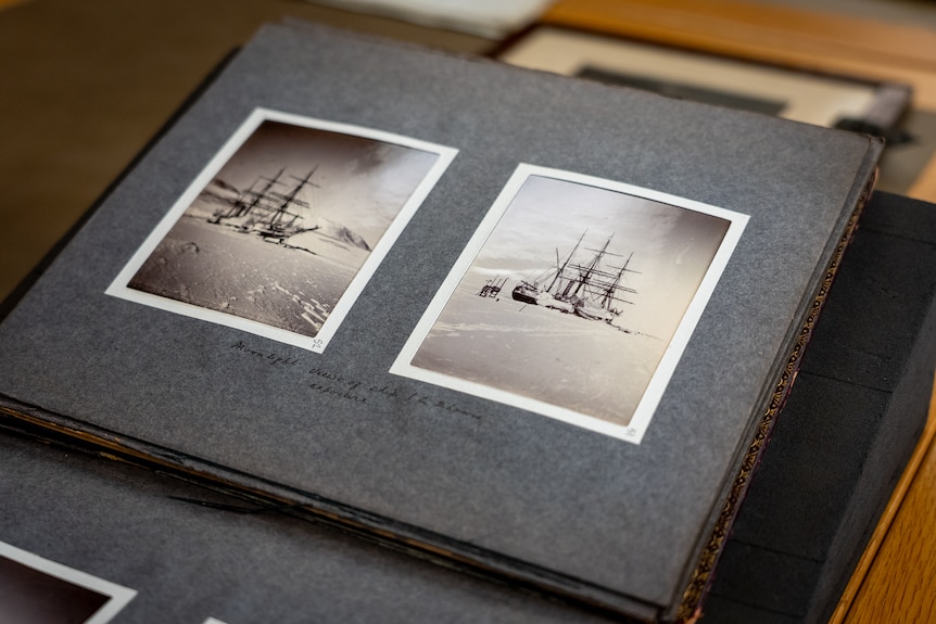 Two black and white photos of a tall ship surrounded by ice are bound in a book