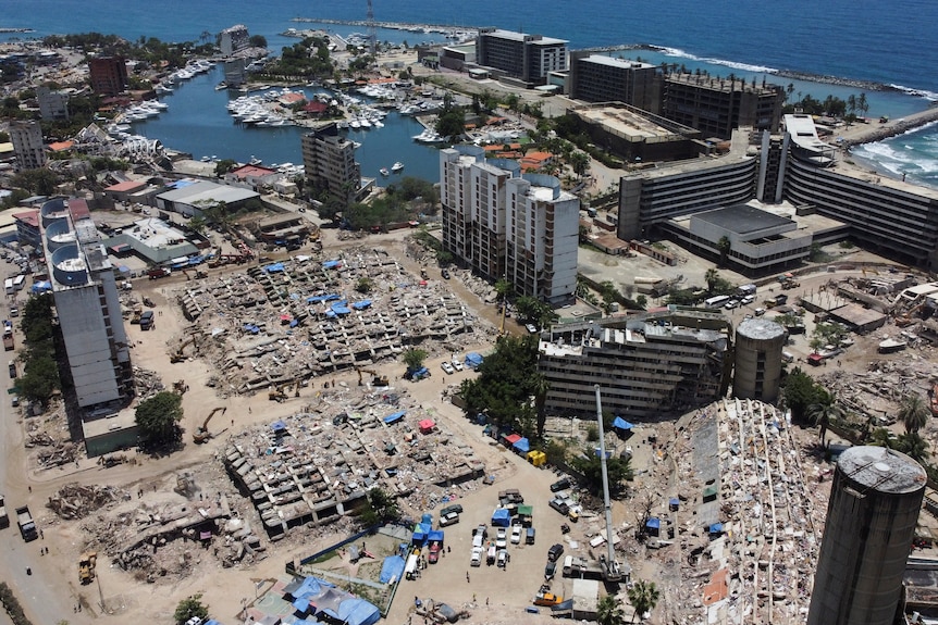 A drone view of flattened buildings by the beach.
