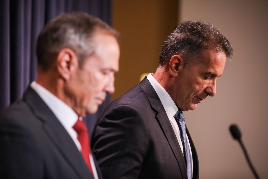 Two men in suits standing together at a podium