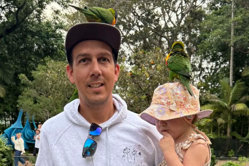 Leigh Peters and his kids pose with lorikeets.