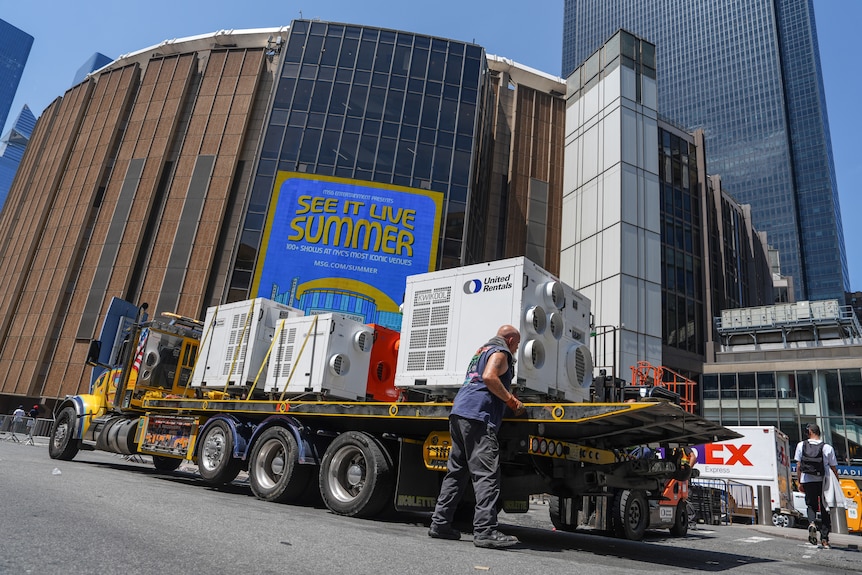 A workers unloads an air con off a truck.