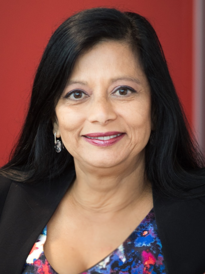 Jayashri Kulkarni wears her dark hair down. She is sitting and smiling at the camera.