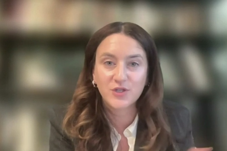 Hannah Rose in a blazer, with brunette hair, speaking before the commission.