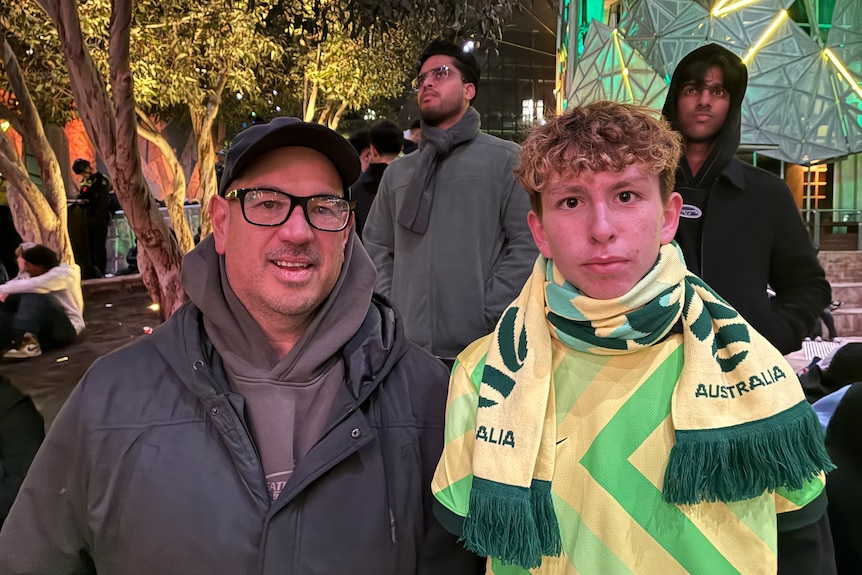 Man with glasses stands next to young man in Australian colours.