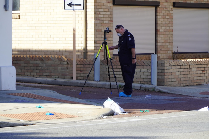 A forensic officer is investigating a crime in a street.