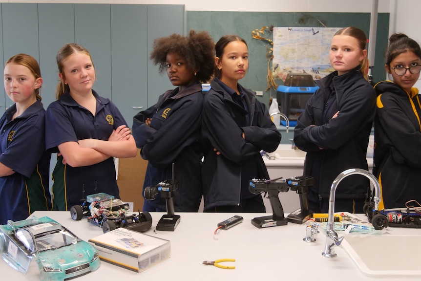Seven teenage girls in school uniform in a school lab with a hydogen remote carr