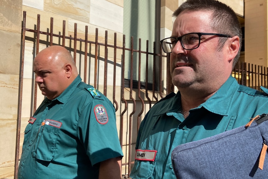 Two men in paramedic uniform walk outside a court house