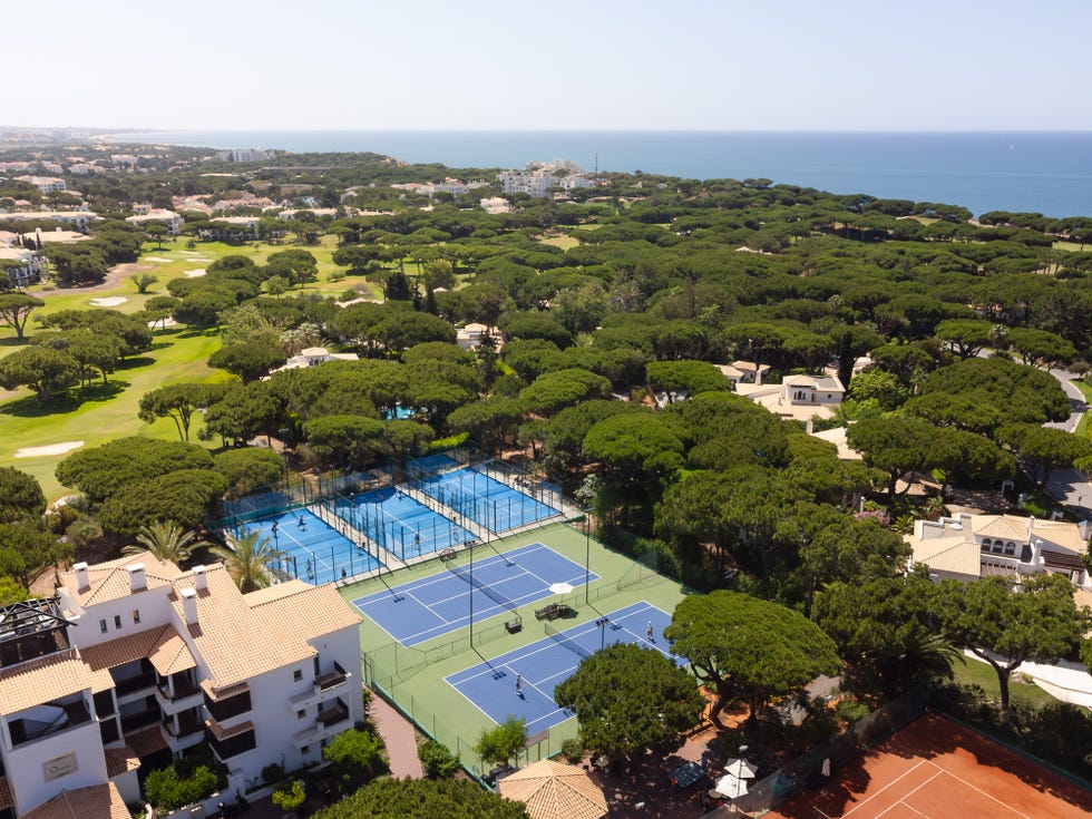 Annabel Croft Pine Cliffs Resort tennis courts surrounded by trees near a golf course and ocean in a resort setting
