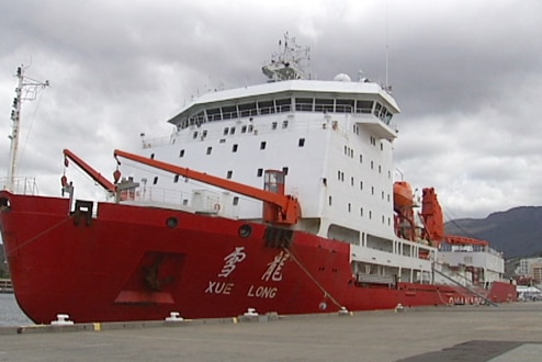 A ship at dock with red hull and white superstructure.