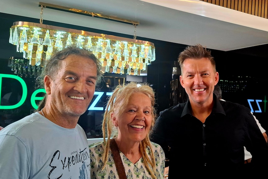 AN older couple standing with former cricketer Brett Lee